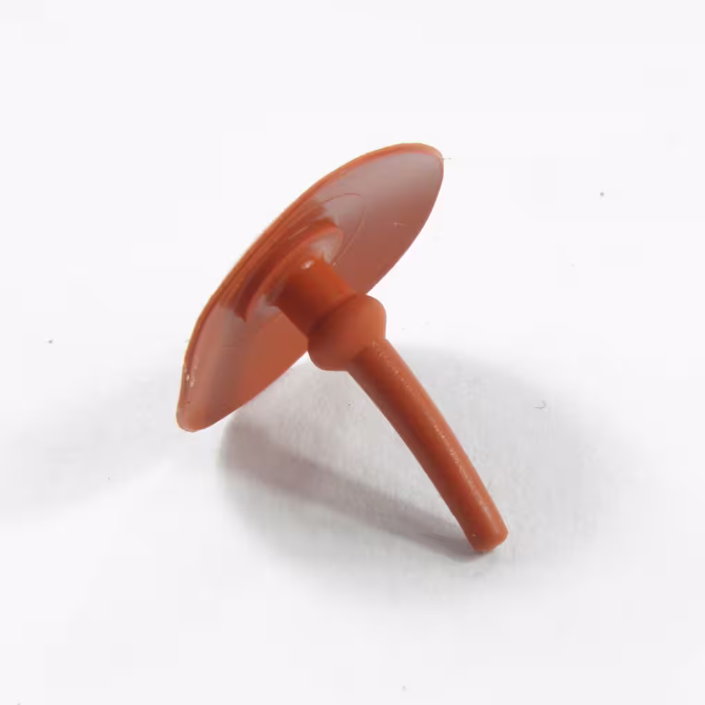 Pomarańczowy, gumowy, zawór odpowietrznika firmy STIHL, nazywany parasolowym , grzybkiem. Widok pod kątem na białym tle.